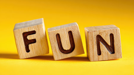 Playful wooden blocks spelling out fun arranged on a vibrant yellow background, perfect for conveying joy, creativity, and positive energy in design projects.の素材