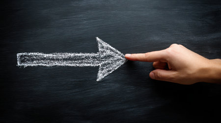 Hand Pointing at Chalk Arrow on Dark Blackboard Surface for Direction and Guidance, Concept of Leadership and Decision-Making in Education and Businessの素材