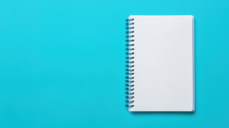 Blank spiral notebook on turquoise surface, ideal for notes, sketches, and creative ideas, perfect for students and professionals in various fieldsの素材