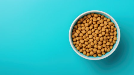 Close-up View of a Bowl Filled with Small Crispy Golden Snacks Against a Bright Blue Backgroundの素材