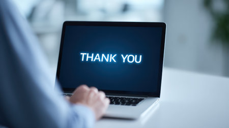 Computer Screen Displaying a Bright "Thank You" Message with a Person's Hand Positioned on the Keyboard in a Modern Office Environmentの素材