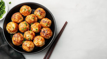 A plate of golden-brown takoyaki balls garnished with green onions, served with chopsticks on a light surface.の素材