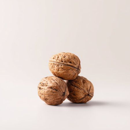 Three Whole Walnuts on a Light Background Highlighting Natural Texture and Shape for Healthy Food and Culinary Conceptsの素材