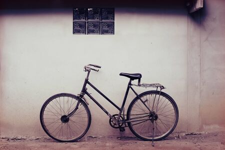 Old rusty vintage bicycle near the concrete wall at homeの写真素材