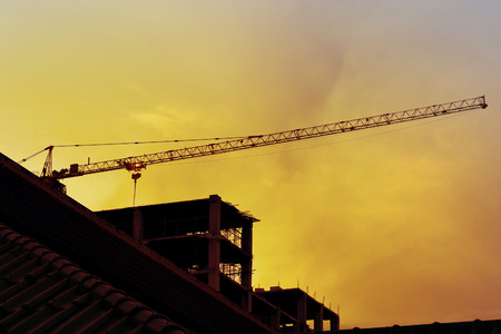 Construction cranes and Buildings Backlit on evening skyの写真素材