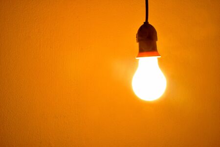 Incandescent light bulb orange light on wallの写真素材