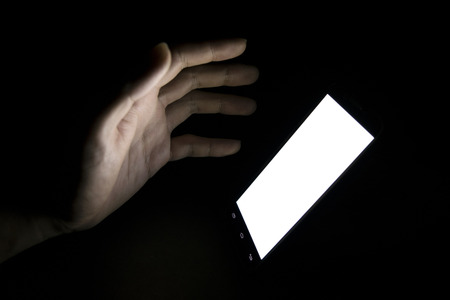 finger touch white screen Mobile telephone in the darkroomの写真素材