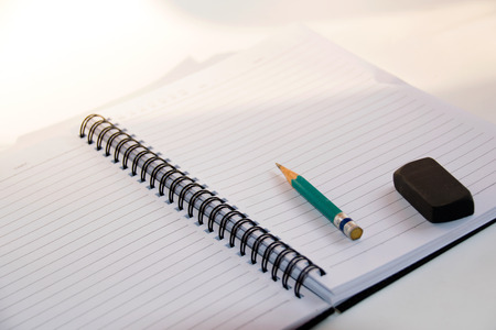 Close up Green Pencil and black eraser placed on a notebookの写真素材