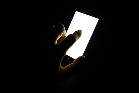 finger touch on white screen Mobile telephone in the darkroom