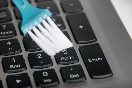 Close up holding blue brush to clean on keyboard laptopの写真素材