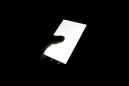 Close up hand holding mobile phone and Touch white screen in dark room