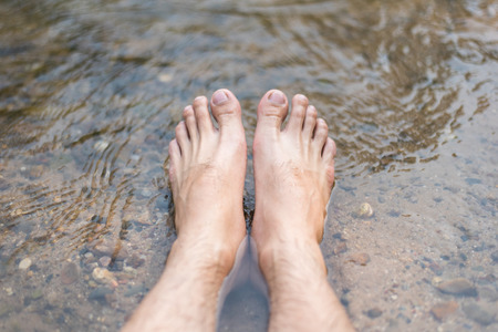 Close up Men's feet are soaked in streams riverの写真素材