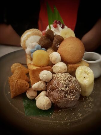 toast with variety of thai dessert sweets decoration and syrup with banana and chocolate ice creamの写真素材