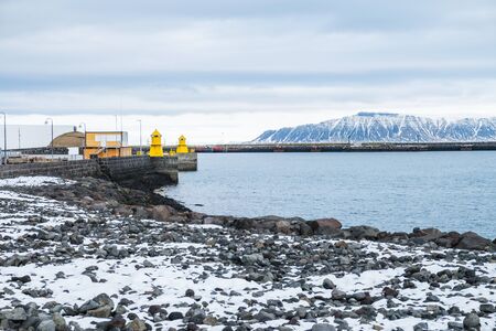 Beautiful view of Iceland winter season and Yellow lighthouse tower on stone breakwater rekjavik...