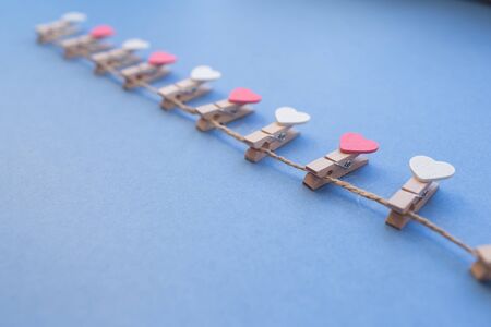 Clothespins with hearts with the twine lay a blue background