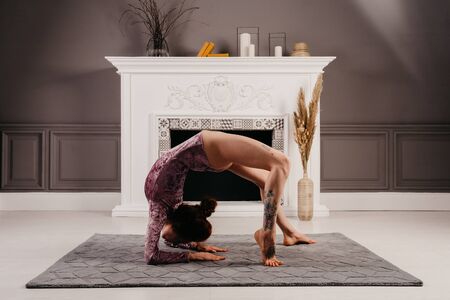 Very flexible young girl doing yoga in the minimalism room