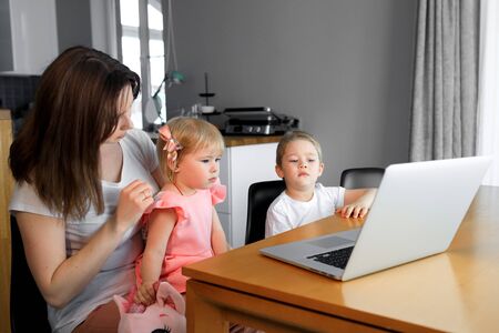 A mother with a young son and daughter watching educational programs on a laptopの写真素材