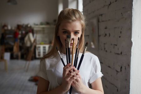 A young artist stands in a painting Studio with brushes.の写真素材