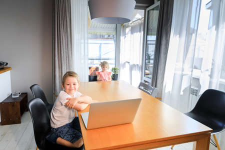 A person sitting at a table with a laptop and smiling at the cameraの写真素材