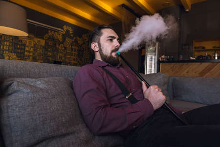 Men relax and smoke hookah in a stylish loft cafe with a modern design