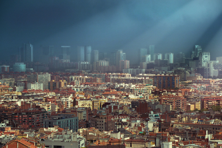 Heavy dark clouds over the skyline of Barcelona partly light of sunbeamの写真素材