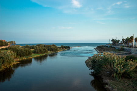End of the Besos river flowing across green plants and outfalls into the sea, Besos del Mar, Barcelonaの写真素材
