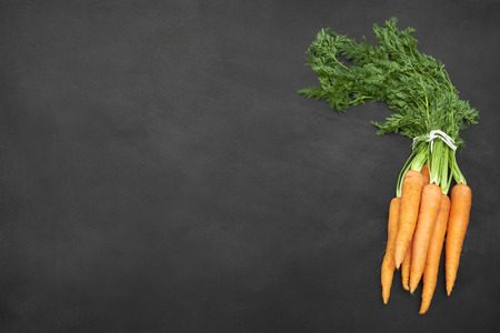 Fresh and juicy carrots bunch on top the old blackboardの写真素材