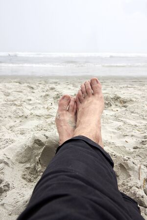 Men feet without shoes on the ocean coast, sandy beach.