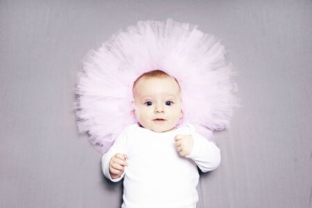 Baby girl in tutu skirt as a pink flower on turquiose backgroundの写真素材