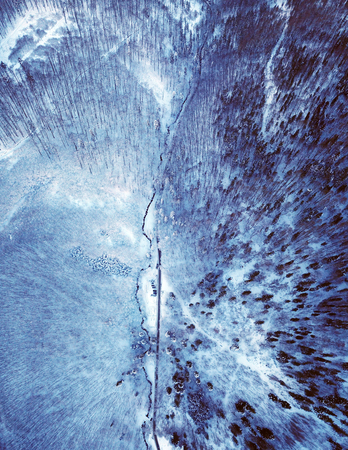 Mountain road in the winter forest aerial view