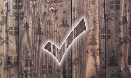 seasonal wooden check symbol on wood with burned in christmas symbols such as snowflakes presents and starsの写真素材