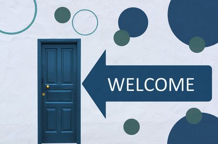 arrow with the word welcome pointing to a unny blue entry door in a white wall with painted circlesの写真素材