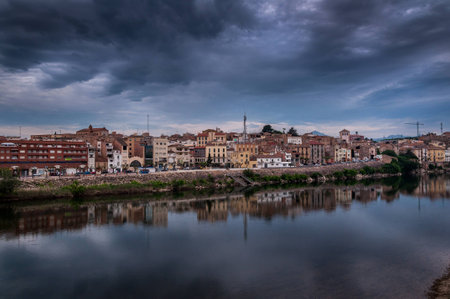 Dramatic view of the village Mora la Nova and the Ebre river at sunrise With cloudy skyの写真素材