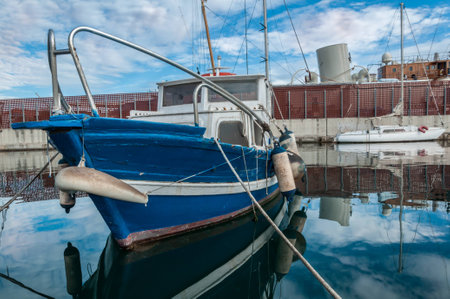 Reflections of fishing boat and a cloudy sky over water in Spainの写真素材