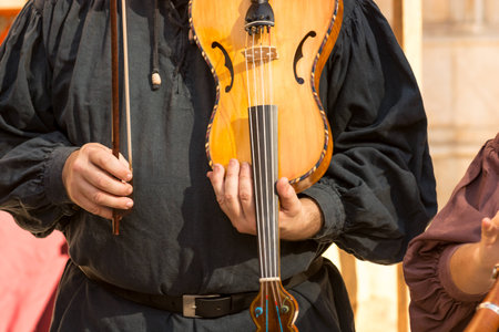 Violinist playing in medieval traditional music group  during medieval market in the town of Montblanc, Tarragona. Spain. Thanks to their music one can feel the atmosphere of a typical medieval market and travel in timeの写真素材