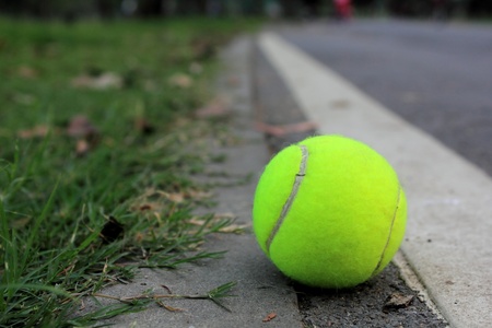 Tennis ball on in the street near a lawn in park の写真素材