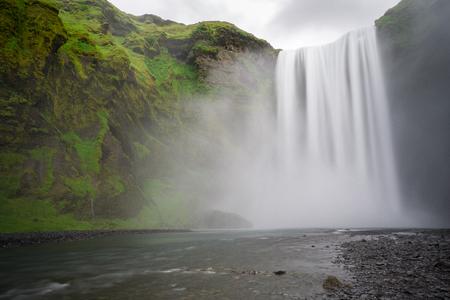 Iceland - Skogafoss waterfall and river with green steep faceの写真素材