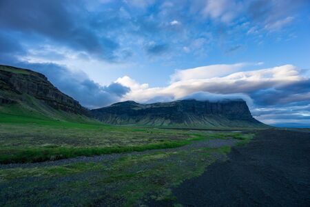 Iceland - Clouds hanging over green volcanic mountains at dawnの写真素材