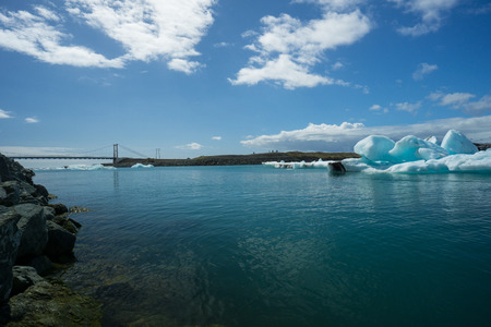 Iceland - Blue glowing icebergs drifting to the ocean before bridge