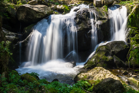 Germany, Sun shining on german triberg waterfalls in between green moss covered stonesの写真素材