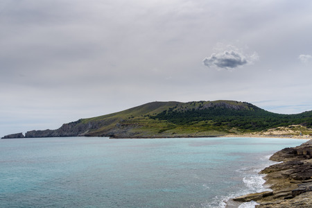 Mallorca, Coastline of Cala Mesquida with tree covered mountainsの写真素材