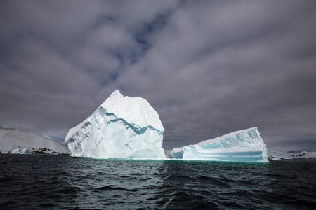 icecaps in the Antarctica with iceberg in the ocean swimming around and melting in the sea