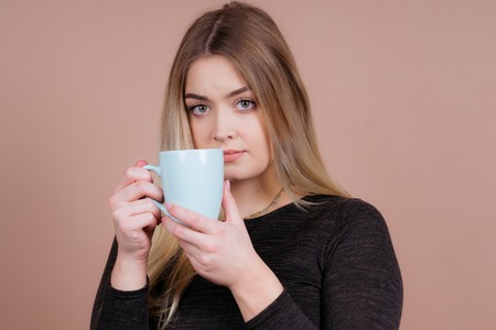 a girl likes to drink a warm cup of coffee and sometimes tea