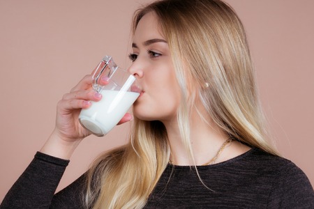 a girl likes to drink milk to stay healthy with a glassの写真素材