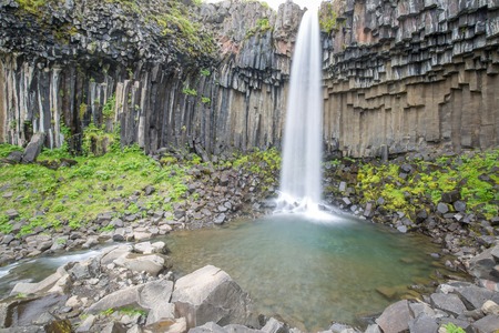 a waterfall in iceland between the mountains from the river spring