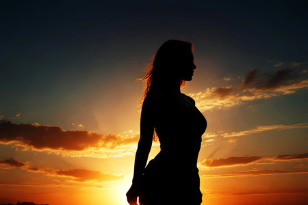 Silhouette of a young woman on the beach at sunset.の写真素材
