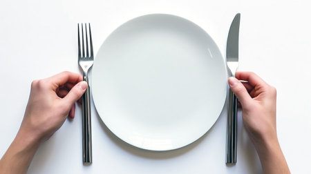 A close-up of hands holding a fork and knife, prepared for a delightful dining experience. A moment of culinary anticipation.の素材
