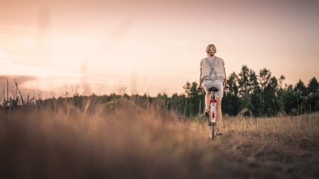 Woman riding a bicycle down a rural roadの写真素材