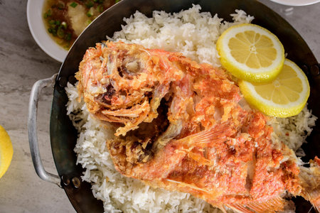 Deliciously Crispy: Top Close-Up of Deep Fried Red Snapper Fish over White Steamed Rice and lemon in 4Kの写真素材