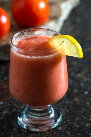 Tomato juice in a glass with lemon and tomatoes on the tableの写真素材